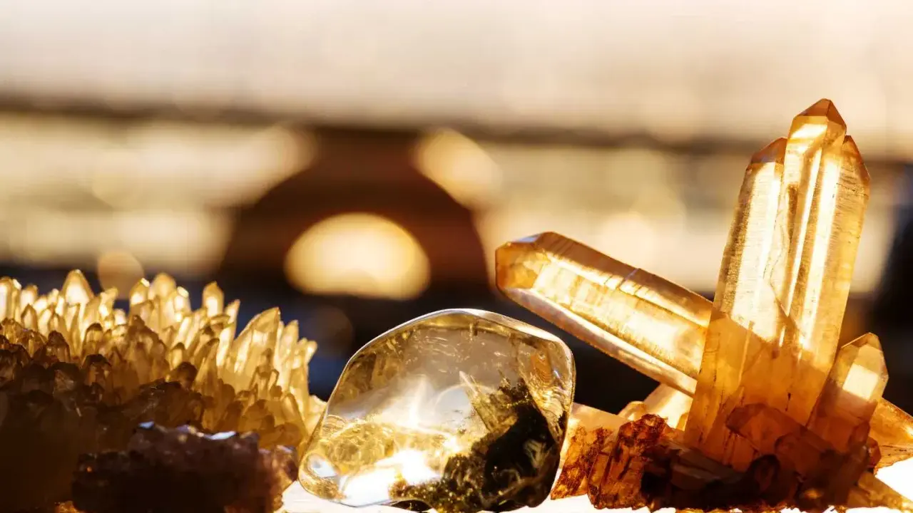 Un amas de cristaux dorés et un cristal poli, baignés de lumière, évoquent la beauté naturelle.