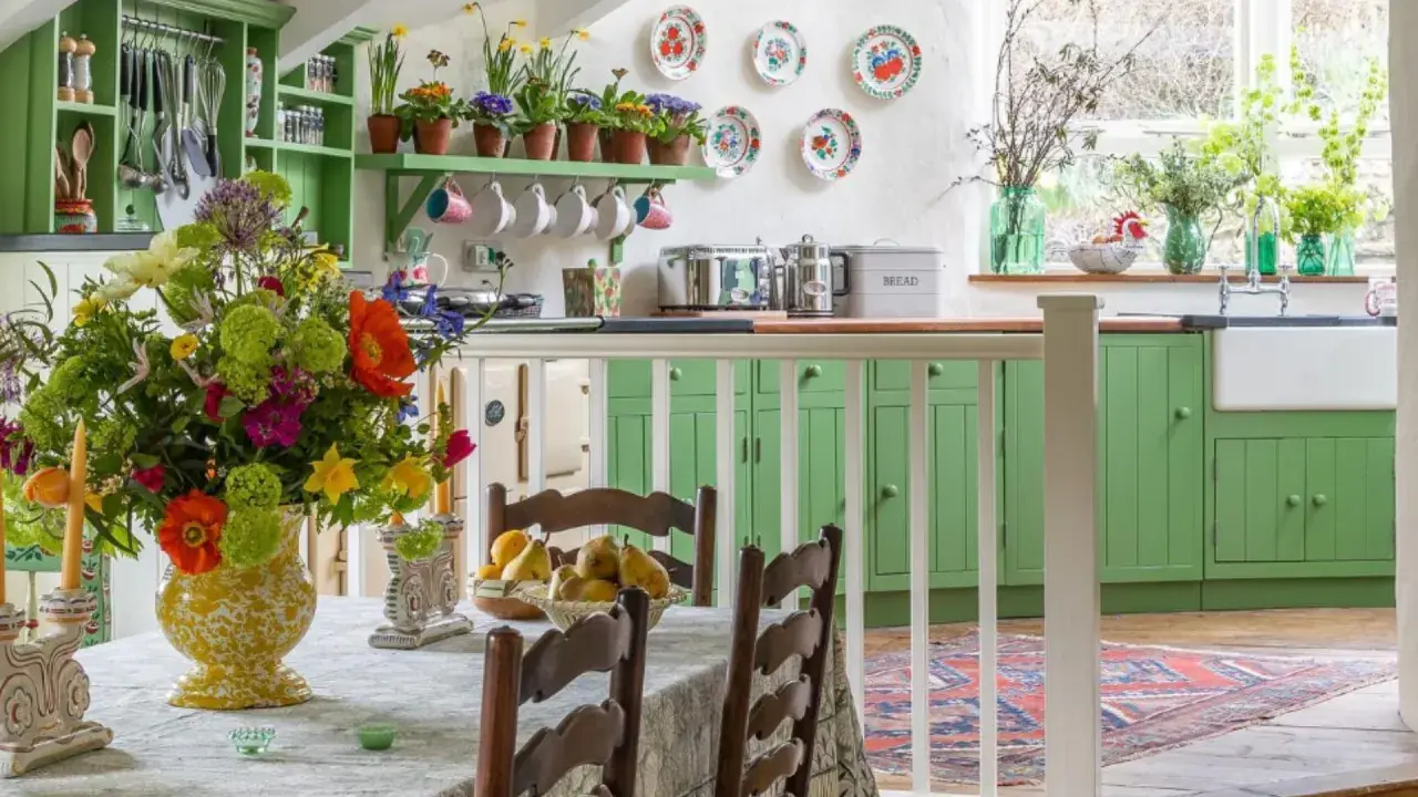 Cuisine lumineuse avec armoires vertes, bouquet de fleurs coloré sur la table, et vaisselle décorative. Ambiance chaleureuse de deco cottage chic.