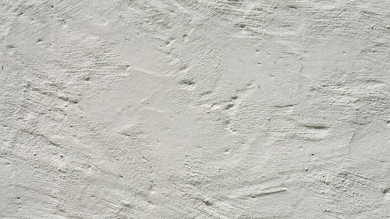 Texture d'enduit à la chaux blanc, présentant des irrégularités et des taches subtiles, témoignant de son application manuelle.