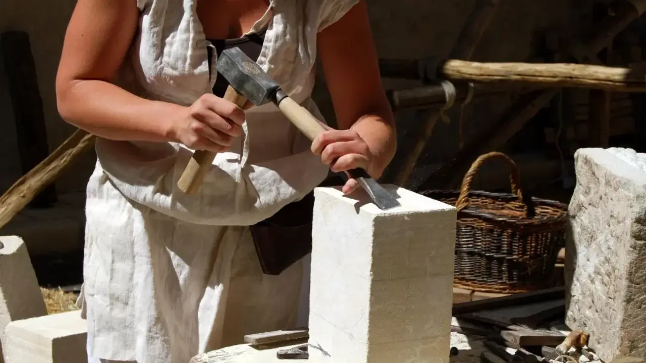 Un artisan tailleur de pierre travaille la pierre avec un marteau et un ciseau.