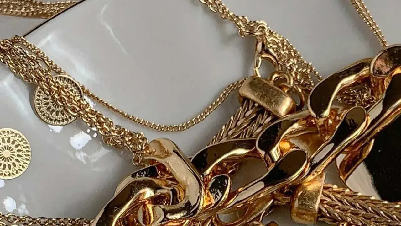 Un bain d'or pour bijoux : des chaînes épaisses et fines, des pendentifs ronds ajourés, un amas de luxe scintillant.