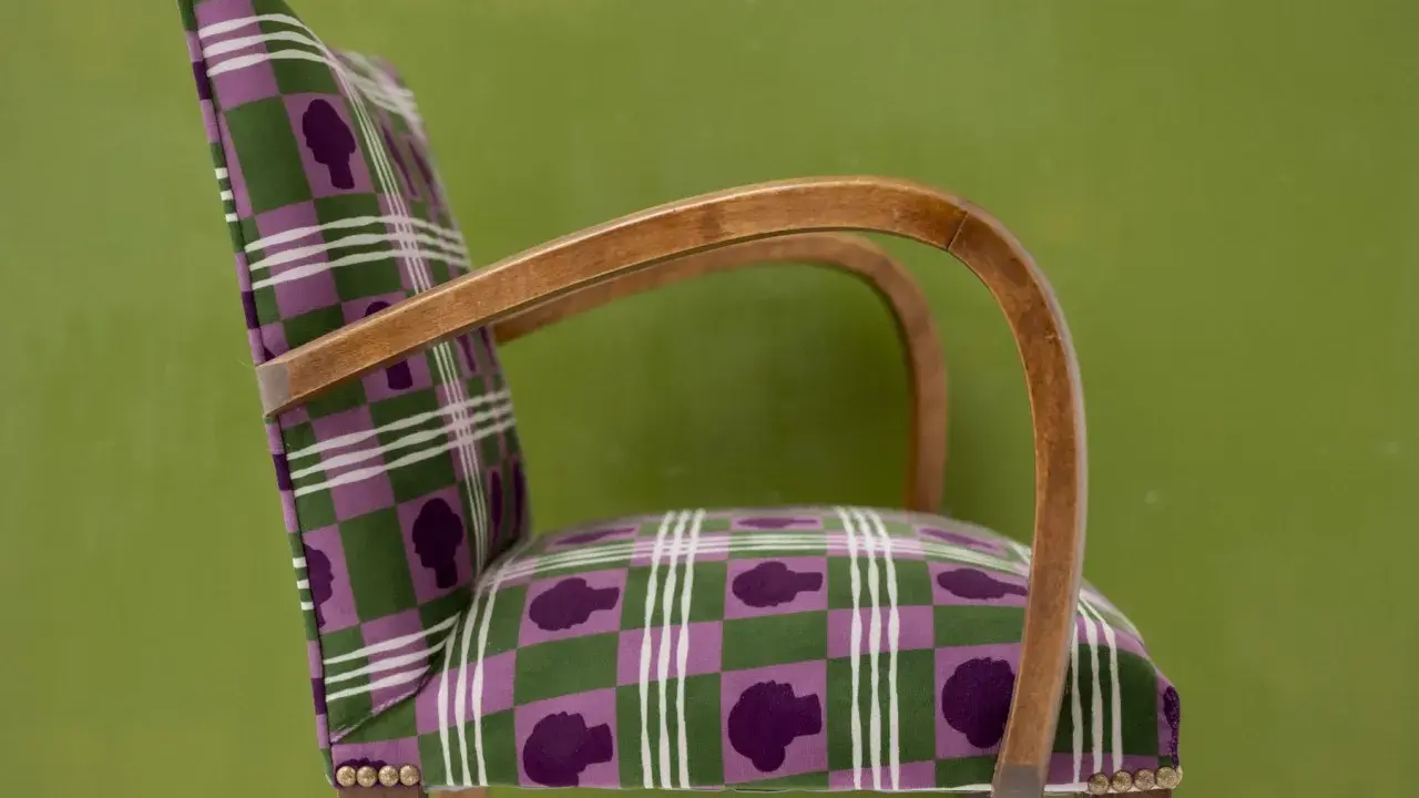 Fauteuil au motif écossais violet et vert, avec des silhouettes de têtes. Un bel exemple d'art tapissier.