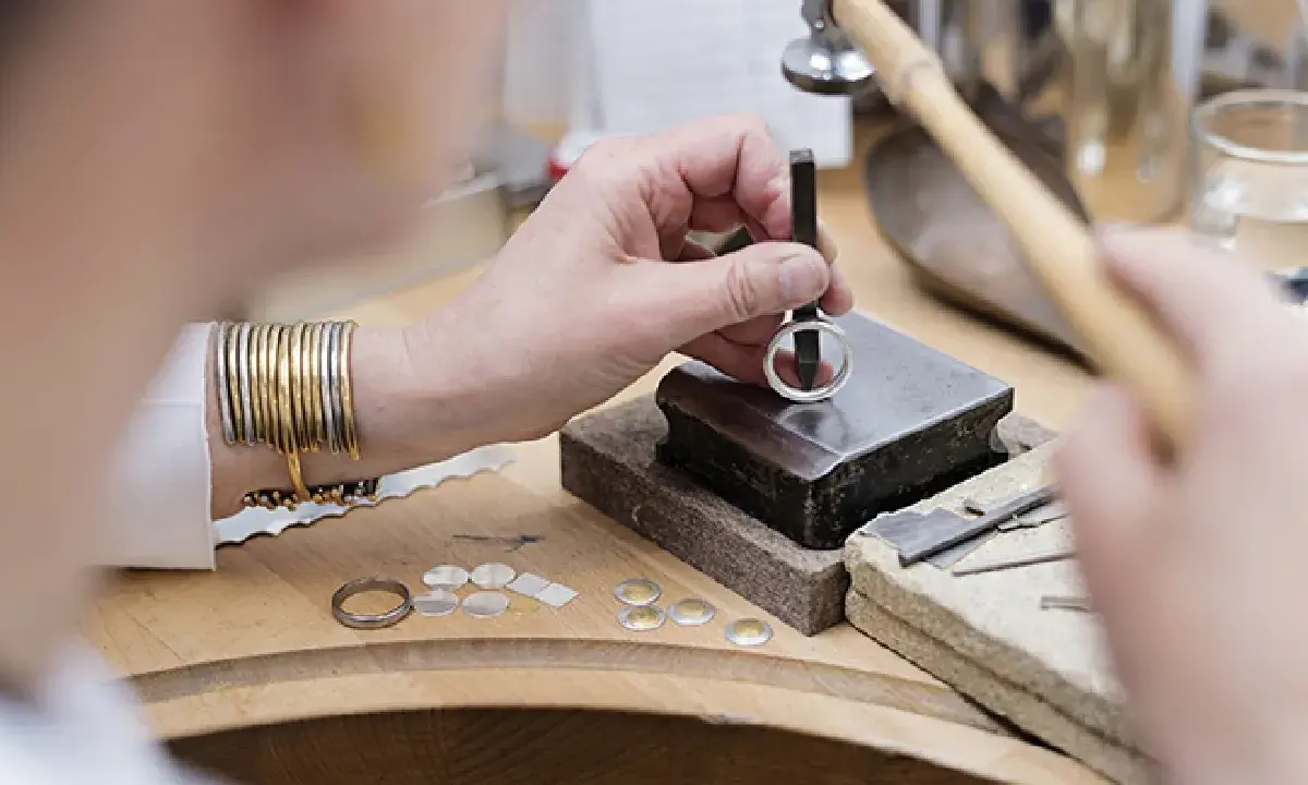 Un orfèvre au travail, façonnant une bague avec précision. Son métier d'orfèvre demande patience et dextérité.