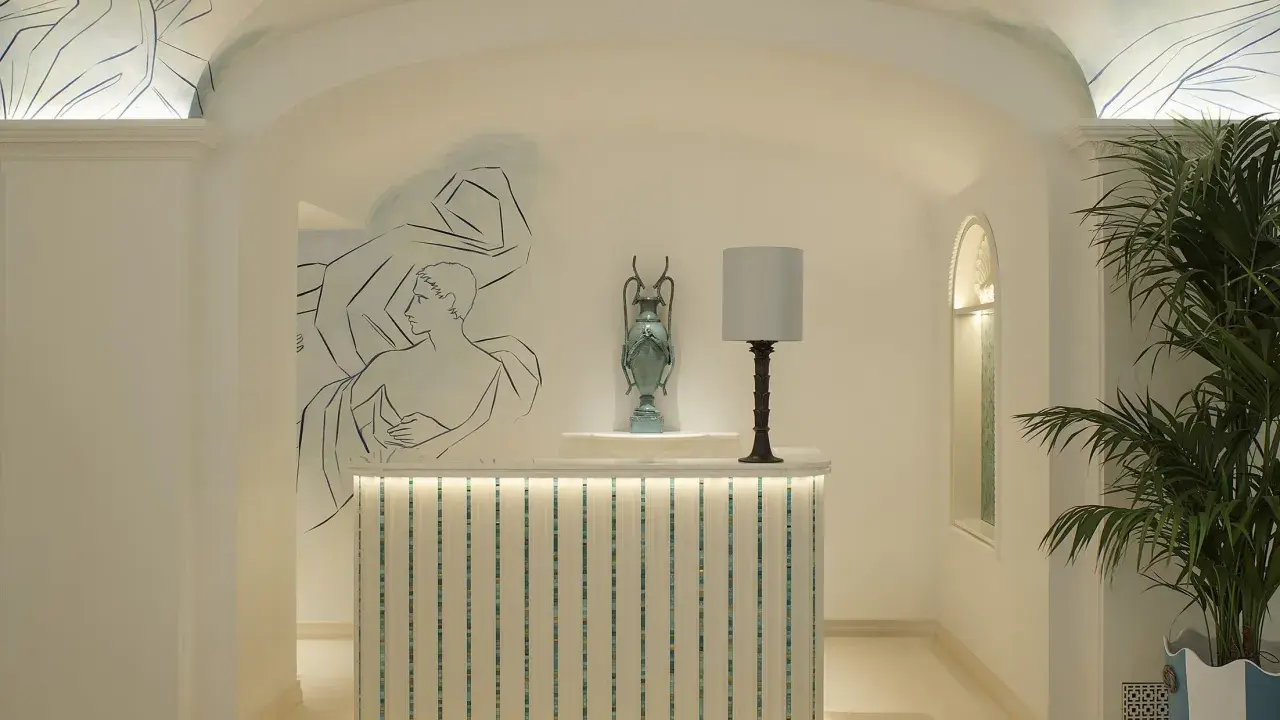 L'entrée art déco dévoile une réception lumineuse, ornée de fresques murales et d'une plante luxuriante.