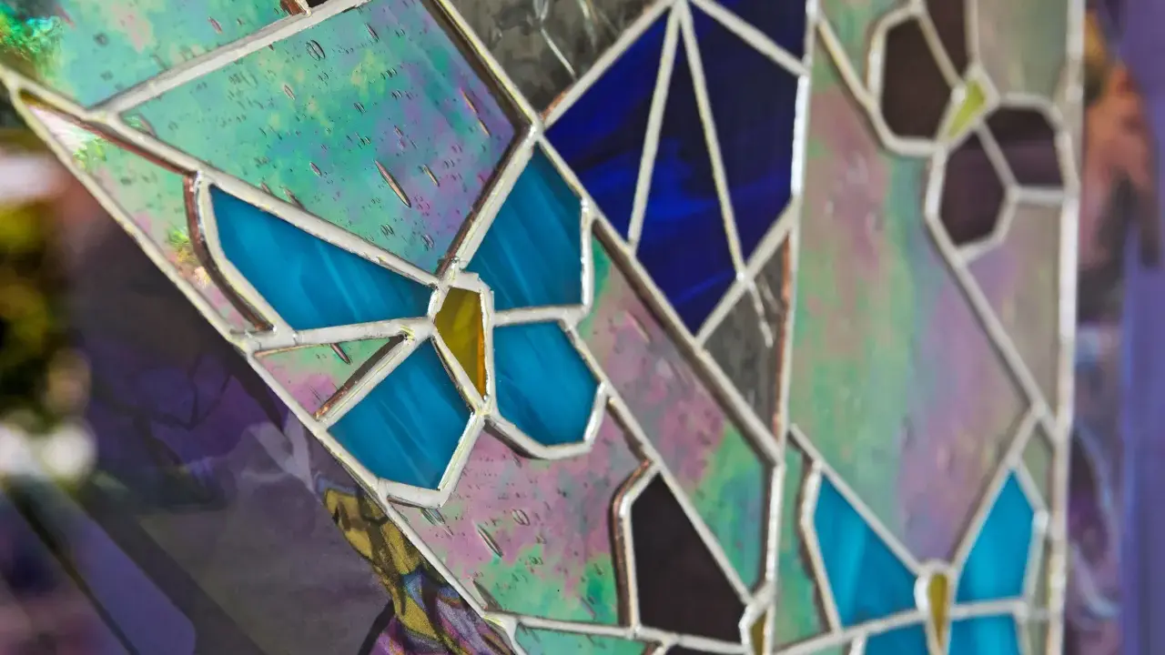 Un vitrail sur mesure aux couleurs vives, avec des motifs de papillons bleus et des éclats irisés.