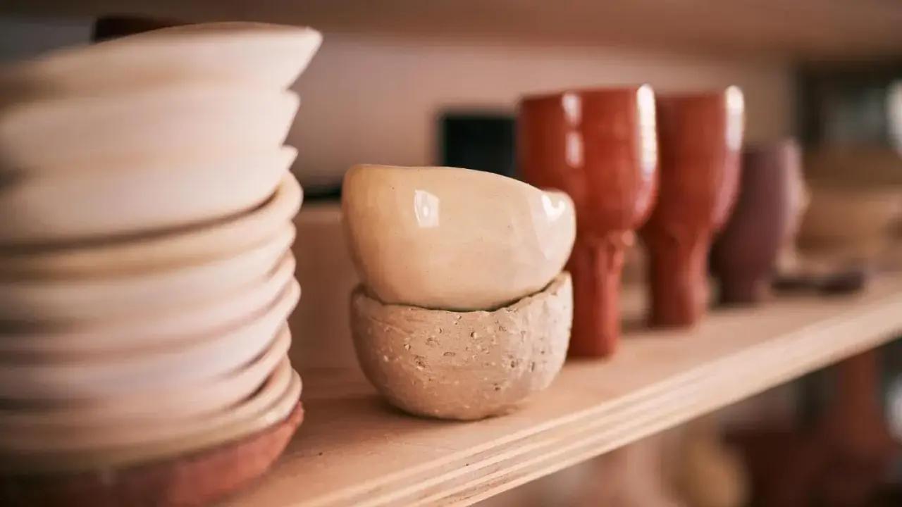 Sur une étagère en bois, des bols et des gobelets en terre cuite, œuvres d'un céramiste France, attendent d'être vendus.