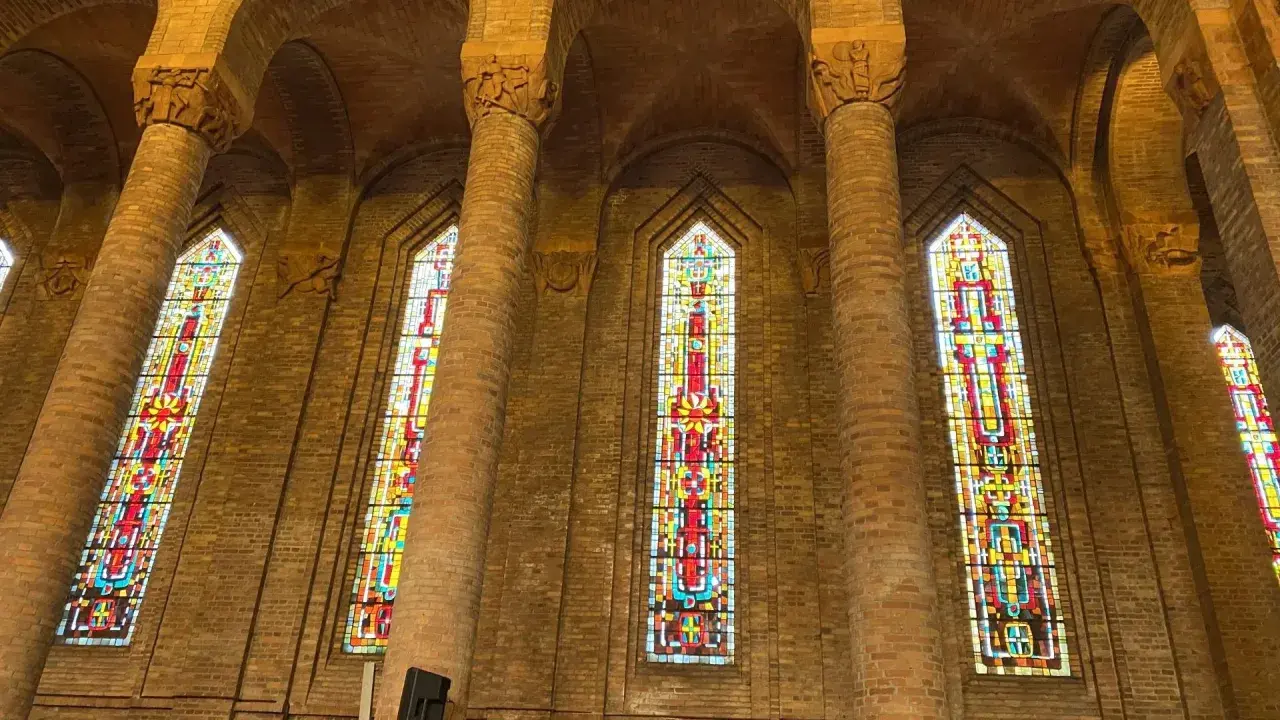 Vitraux colorés illuminant l'intérieur de l'église de Gien, encadrés par de hautes colonnes de briques.