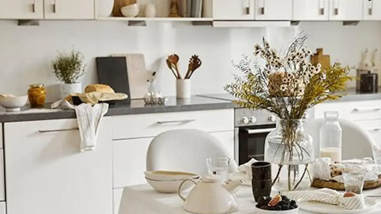 Cuisine lumineuse et aérée, style cottage. Table dressée avec théière, fleurs séchées et pain frais.