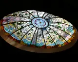Magnifique vitrail intérieur maison, orné de fleurs roses et de motifs végétaux bleus et jaunes, illuminant la pièce.