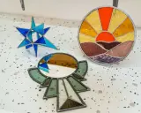Trois pièces d'art en vitrail : une étoile bleue, un soleil couchant et un miroir ornemental. Créations d'un atelier vitrail Paris.