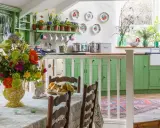 Cuisine lumineuse avec armoires vertes, bouquet de fleurs coloré sur la table, et vaisselle décorative. Ambiance chaleureuse de deco cottage chic.