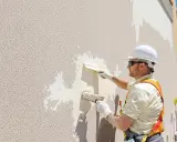Un ouvrier applique un enduit texturé sur un mur extérieur. Le **pigment enduit** est appliqué avec une truelle pour créer une finition texturée.