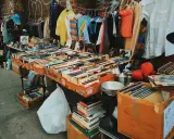Un étalage de brocante rempli de livres, disques vinyles et vêtements. Les livres sont les objets les plus recherchés en brocante, et cette sélection en est la preuve.