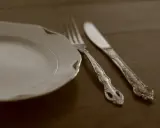 Une assiette blanche et des couverts en métal argenté, prêts pour un repas. L'art de nettoyer des couverts en métal argenté pour qu'ils brillent.