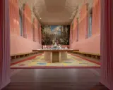 Installation d'art contemporain à Venise, évoquant le *homo faber*. Un tapis coloré et une table ornée de sculptures sous un grand tableau.