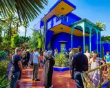 Visiteurs admirant l'architecture vibrante et la végétation luxuriante du jardin Majorelle, un havre de paix bleu cobalt et jaune.