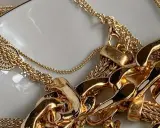 Un bain d'or pour bijoux : des chaînes épaisses et fines, des pendentifs ronds ajourés, un amas de luxe scintillant.