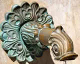 Robinet en laiton orné, avec des traces de vert-de-gris.