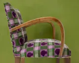 Fauteuil au motif écossais violet et vert, avec des silhouettes de têtes. Un bel exemple d'art tapissier.
