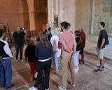 Visite guidée dans l'abbaye du Thoronet. Un groupe de touristes écoute attentivement un guide présentant l'architecture cistercienne.