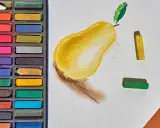 Boîte de pastels secs et une poire dessinée. Apprenez comment faire des pastel en utilisant ces couleurs vives.
