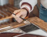 Main d'un artisan travaillant sur un vitrail, un exemple de métiers rares et recherchés.