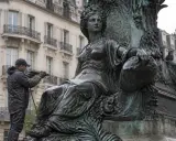 Un homme nettoie une statue en bronze avec un jet d'eau. Il apprend comment nettoyer le bronze pour redonner son éclat à l'œuvre.