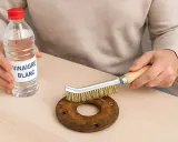 Une personne utilise du vinaigre blanc et une brosse métallique pour nettoyer du métal rouillé.