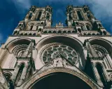 La **cathédrale de Laon**, majestueuse et imposante, se dresse sous un ciel bleu profond. Ses tours jumelles et sa rosace ornée captivent le regard.
