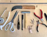 Outils pour le **matériel vitrail** : ruban à mesurer, ciseaux, couteau, marteau, pinces, clous et petits morceaux de bois.