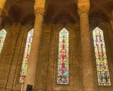 Vitraux colorés illuminant l'intérieur de l'église de Gien, encadrés par de hautes colonnes de briques.