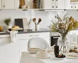 Cuisine lumineuse et aérée, style cottage. Table dressée avec théière, fleurs séchées et pain frais.