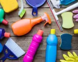 Divers produits et accessoires de nettoyage colorés sur fond de bois.