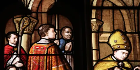 Vitraux de la cathédrale de Nevers : scènes religieuses avec des personnages en habits liturgiques, un évêque coiffé de sa mitre dorée.
