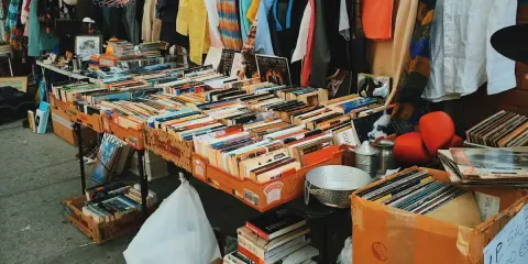 Un étalage de brocante rempli de livres, disques vinyles et vêtements. Les livres sont les objets les plus recherchés en brocante, et cette sélection en est la preuve.