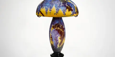 Lampe Art Nouveau d'un artiste verrier, ornée de glycines bleues et de feuilles sur un fond jaune.