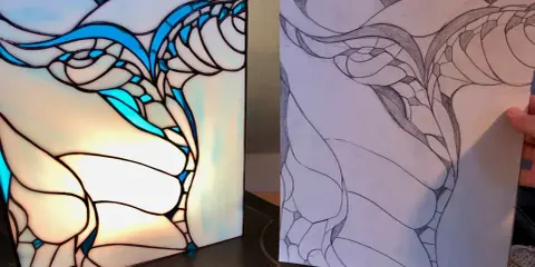 Le vitrail wecandoo, une œuvre d'art lumineuse aux courbes bleues et blanches, est comparé à son croquis préparatoire.