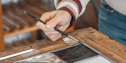 Main d'un artisan travaillant sur un vitrail, un exemple de métiers rares et recherchés.