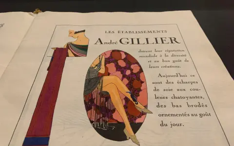 Publicité André Gillier, style art déco, avec une femme aux jambes ornées de bas brodés, rappelant les dates de cette époque.