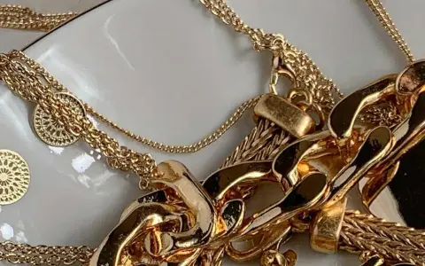 Un bain d'or pour bijoux : des chaînes épaisses et fines, des pendentifs ronds ajourés, un amas de luxe scintillant.