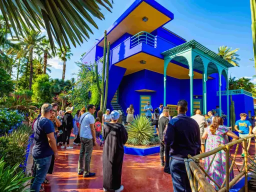 Visiteurs admirant l'architecture vibrante et la végétation luxuriante du jardin Majorelle, un havre de paix bleu cobalt et jaune.
