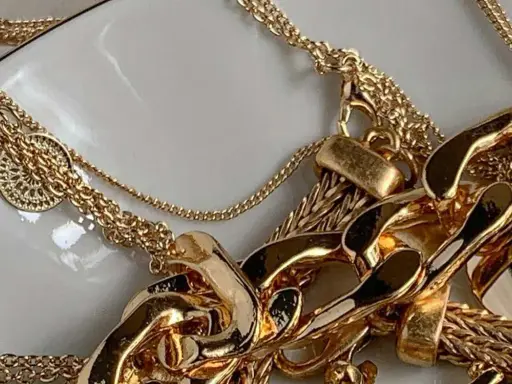 Un bain d'or pour bijoux : des chaînes épaisses et fines, des pendentifs ronds ajourés, un amas de luxe scintillant.