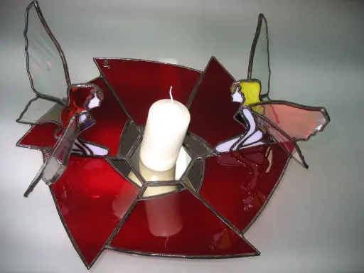 Un photophore vitrail aux couleurs vives, orné de deux anges aux ailes translucides, tenant une bougie blanche.