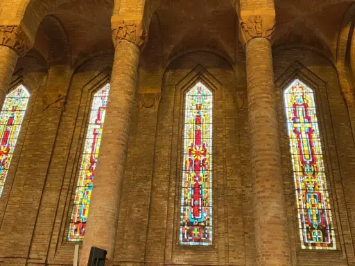 Vitraux colorés illuminant l'intérieur de l'église de Gien, encadrés par de hautes colonnes de briques.