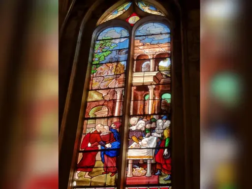 Magnifique **verre d'église** racontant des scènes bibliques, avec des personnages en habits d'époque et des paysages stylisés.