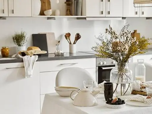 Cuisine lumineuse et aérée, style cottage. Table dressée avec théière, fleurs séchées et pain frais.