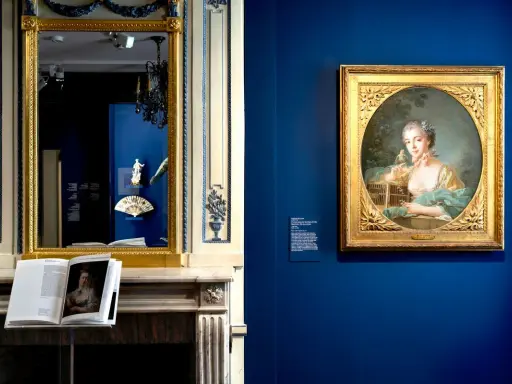 Portrait d'une jeune femme par un peintre français moderne, exposé dans un musée. Un livre ouvert sur une cheminée reflète l'œuvre.