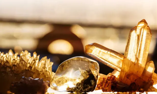 Un amas de cristaux dorés et un cristal poli, baignés de lumière, évoquent la beauté naturelle.