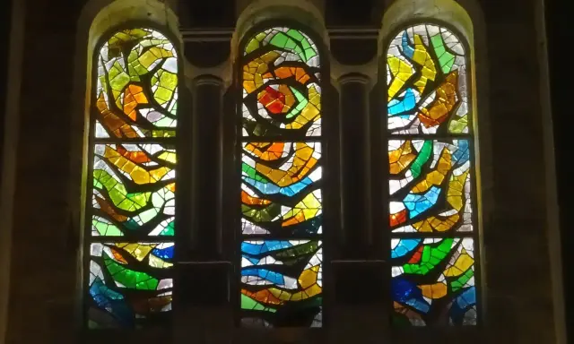Trois vitraux aux formes abstraites et aux couleurs vives, un exemple de comment éclairer un vitrail pour révéler sa beauté.