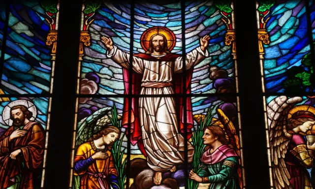 Magnifique vitrail d'église représentant le Christ entouré d'anges et de saints, baigné de lumière.